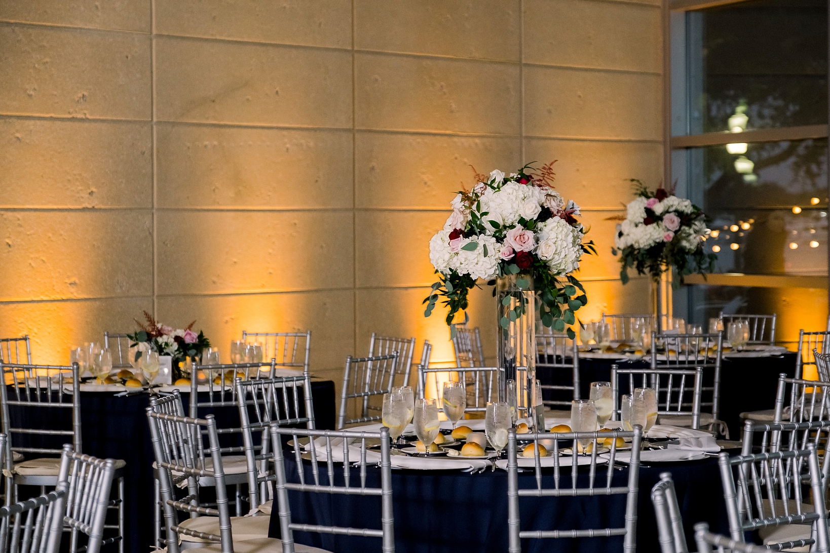 The wedding reception with uplighting and tall floral decor by Sarah & Ben Photography