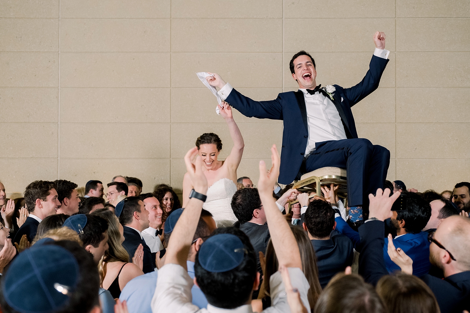 The bride and groom thrust into the air by their wedding guests by Sarah & Ben Photography