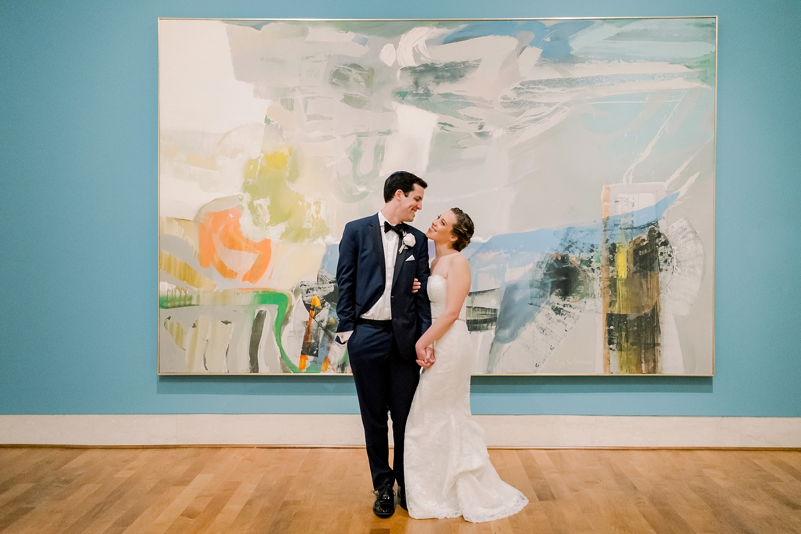 Bride and Groom standing in front of a painting by Sarah & Ben Photography