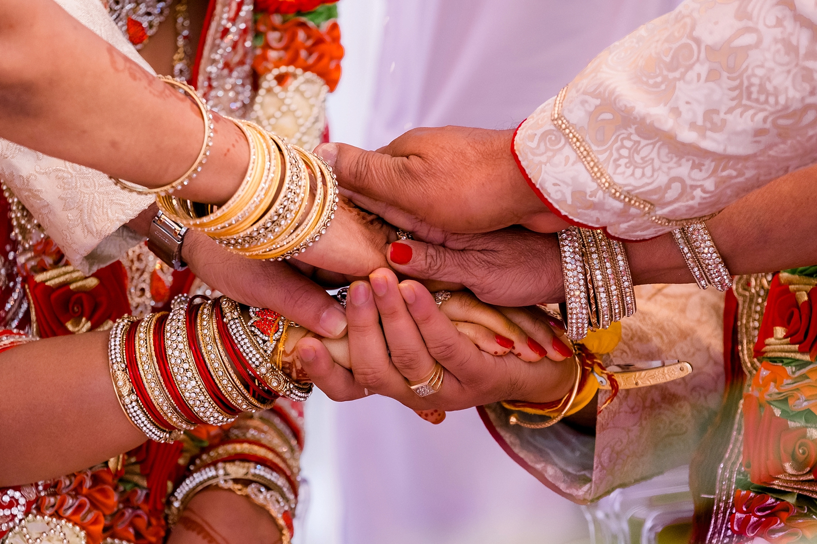The hands of all the family members during the ceremony stacked on top of each other by Sarah & Ben Photography