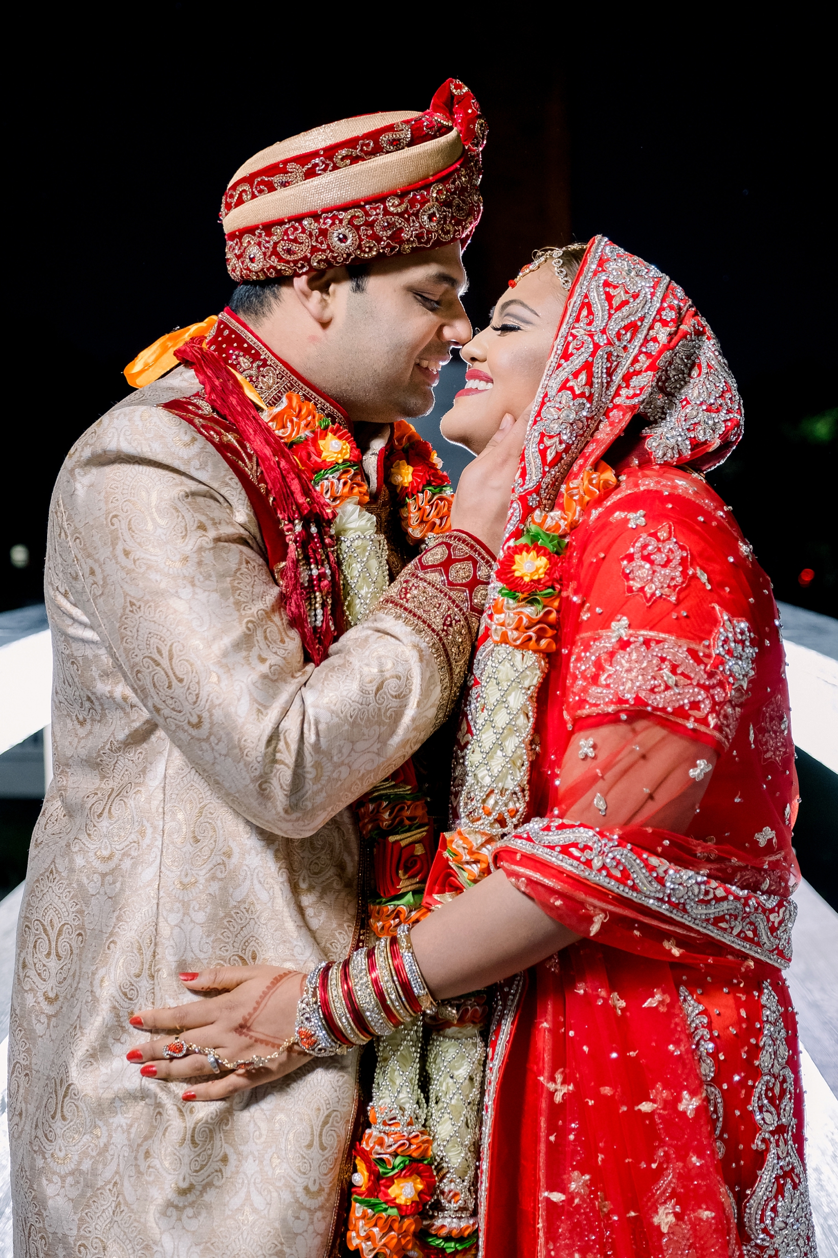 Bride and Groom in full Hindu wedding attire share a near kiss under the stars by Sarah & Ben
