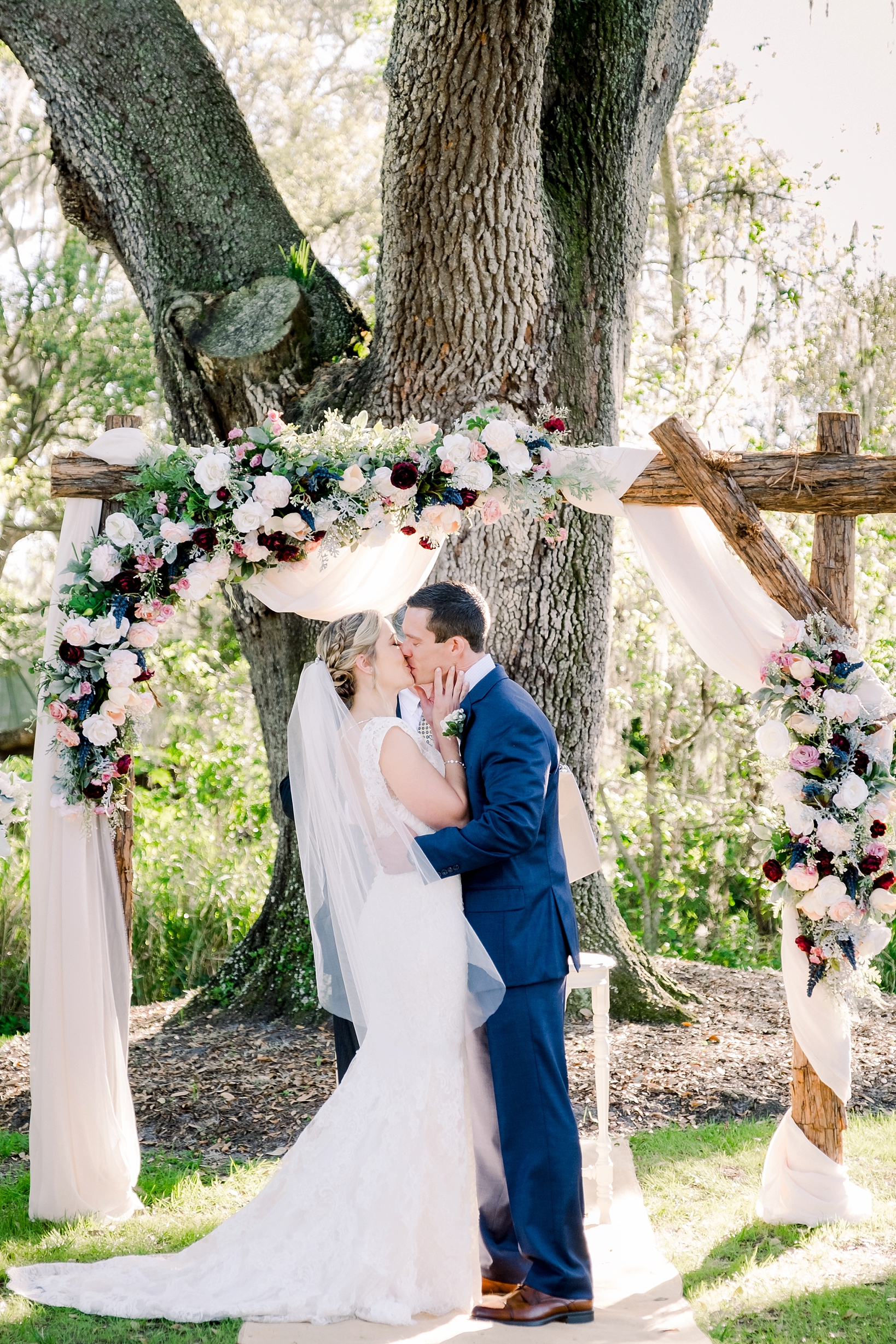 First kiss under their wedding arch by Sarah and Ben Photography