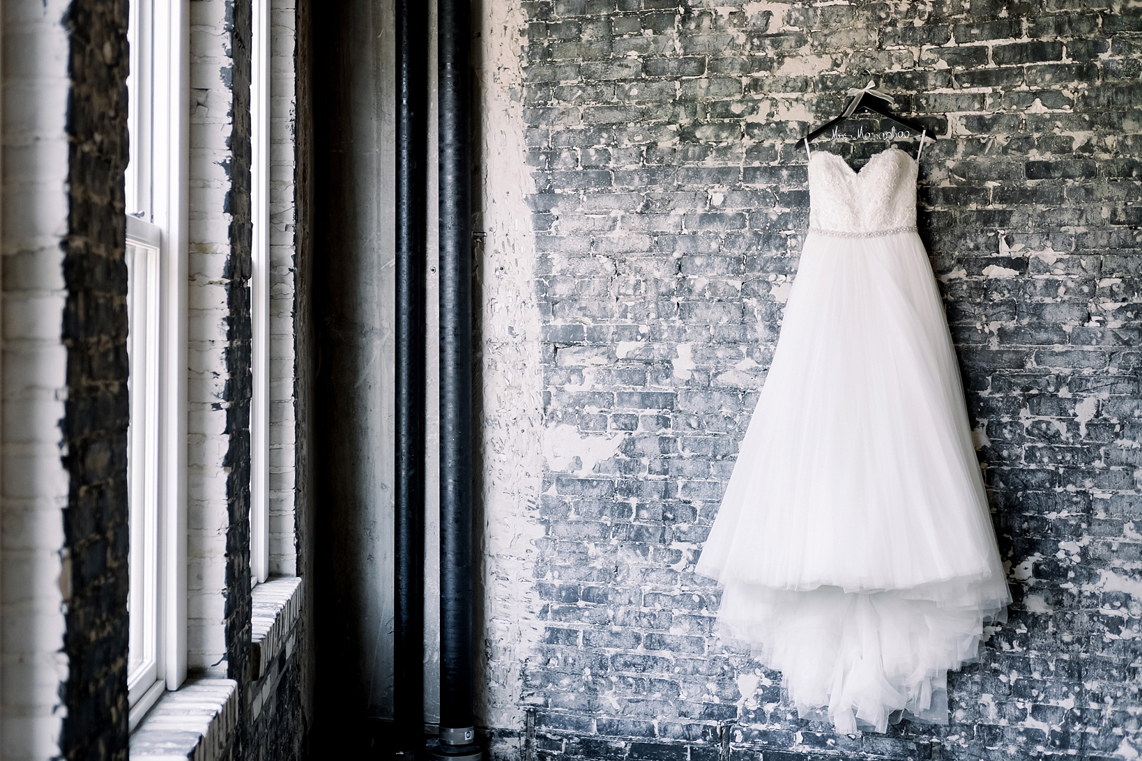 The Wedding Dress hanging on an aged brick wall in the holding room at the Oxford Exchange in Tampa, FL