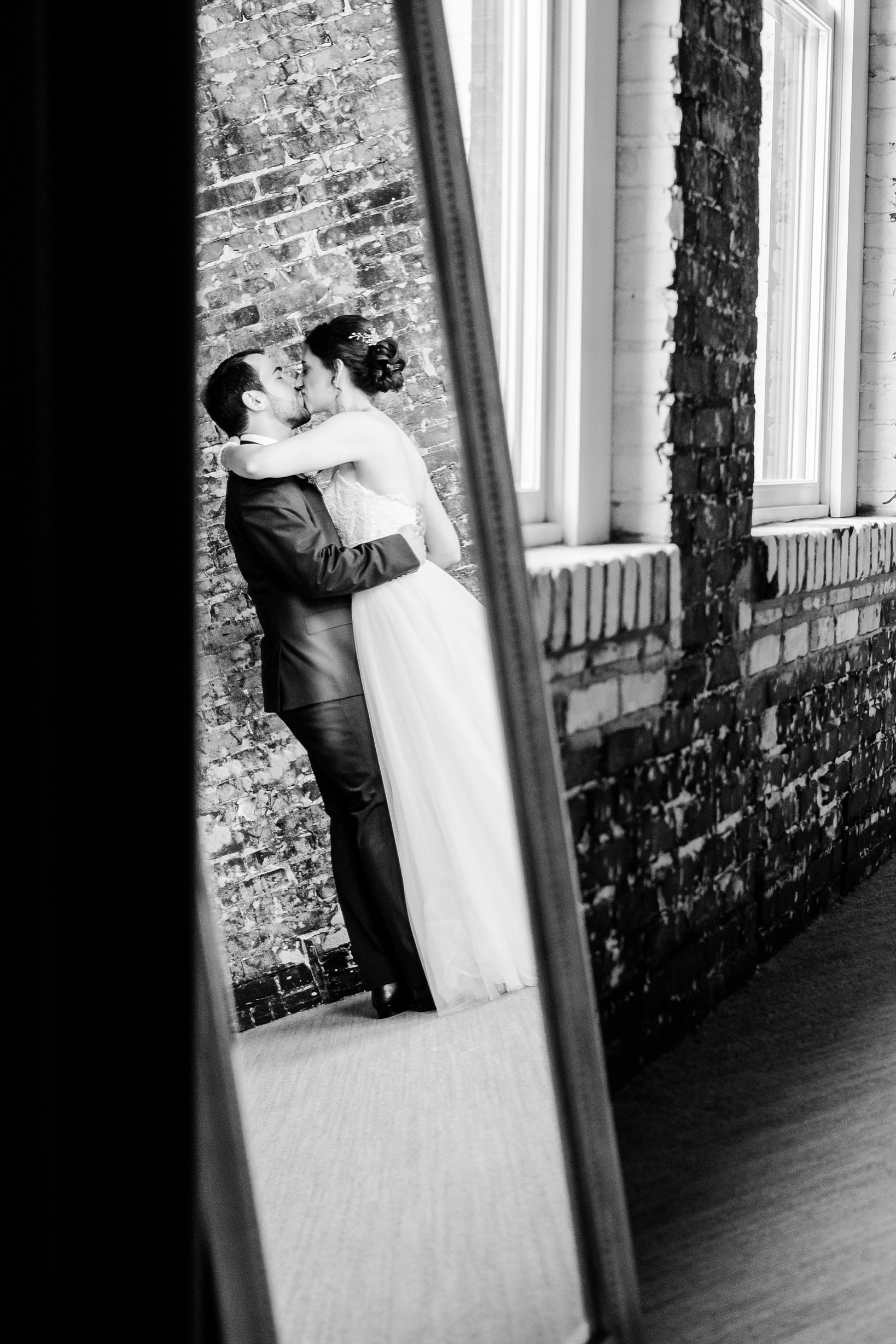 Bride and Groom kissing in the reflection of a mirror by Sarah and Ben Photography