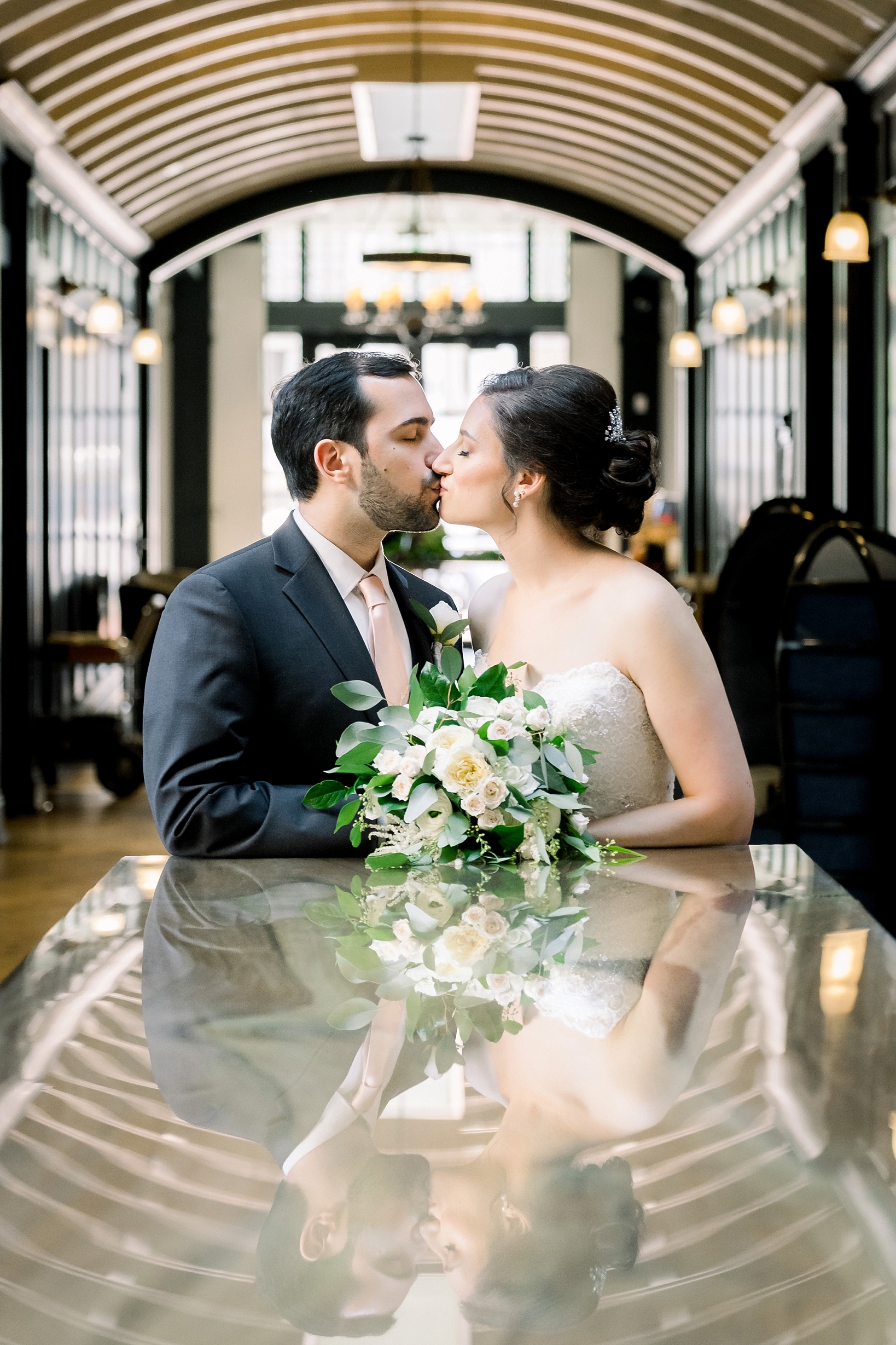 Bride and groom kiss while being reflected in the glass table in their reception on an oxford exchange wedding day