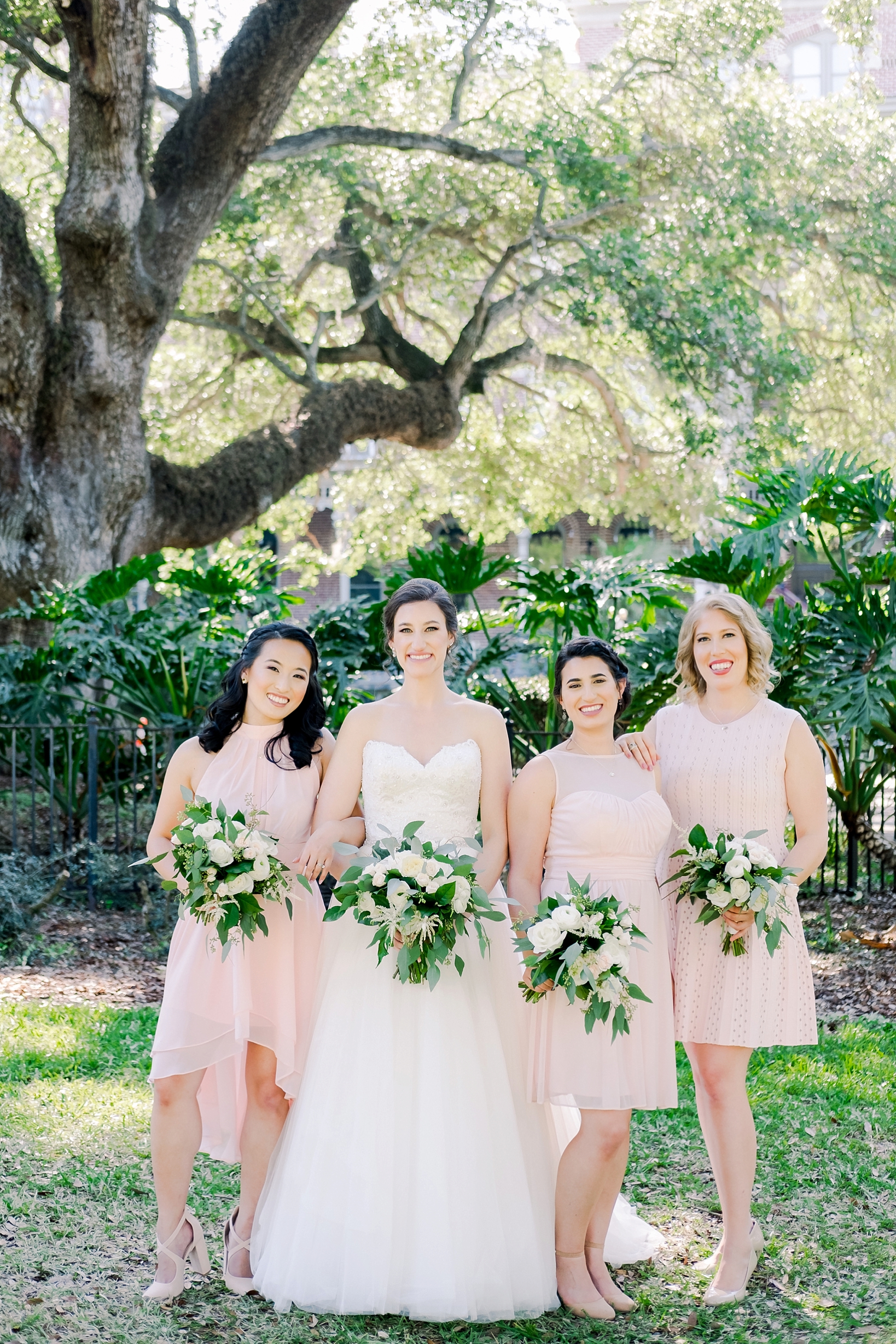 Bride and her Bridesmaids pose for a formal photo under the oak trees of the UT campus