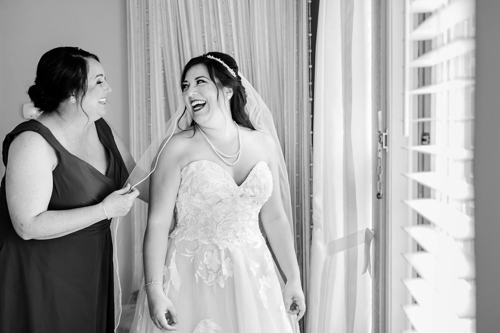 Timeless black and white photo of a Bride and her Bridesmaid sharing a laugh