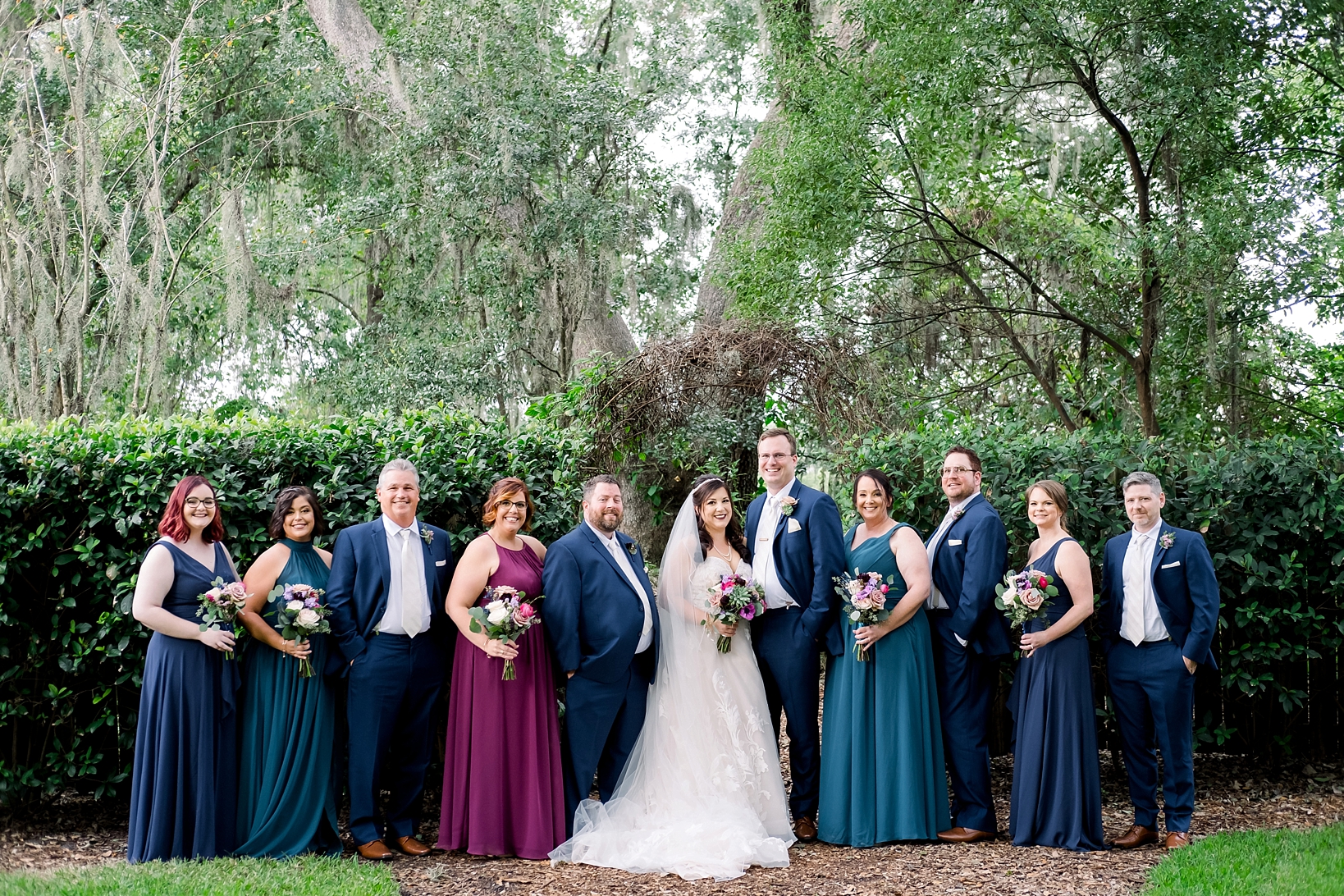 Wedding Party poses along a large wall of greenery on the cross creek ranch gardens