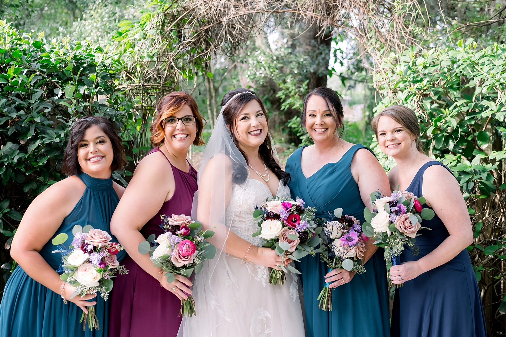 Bride and her Bridesmaids pose holding their bouquets by Sarah and Ben Photography