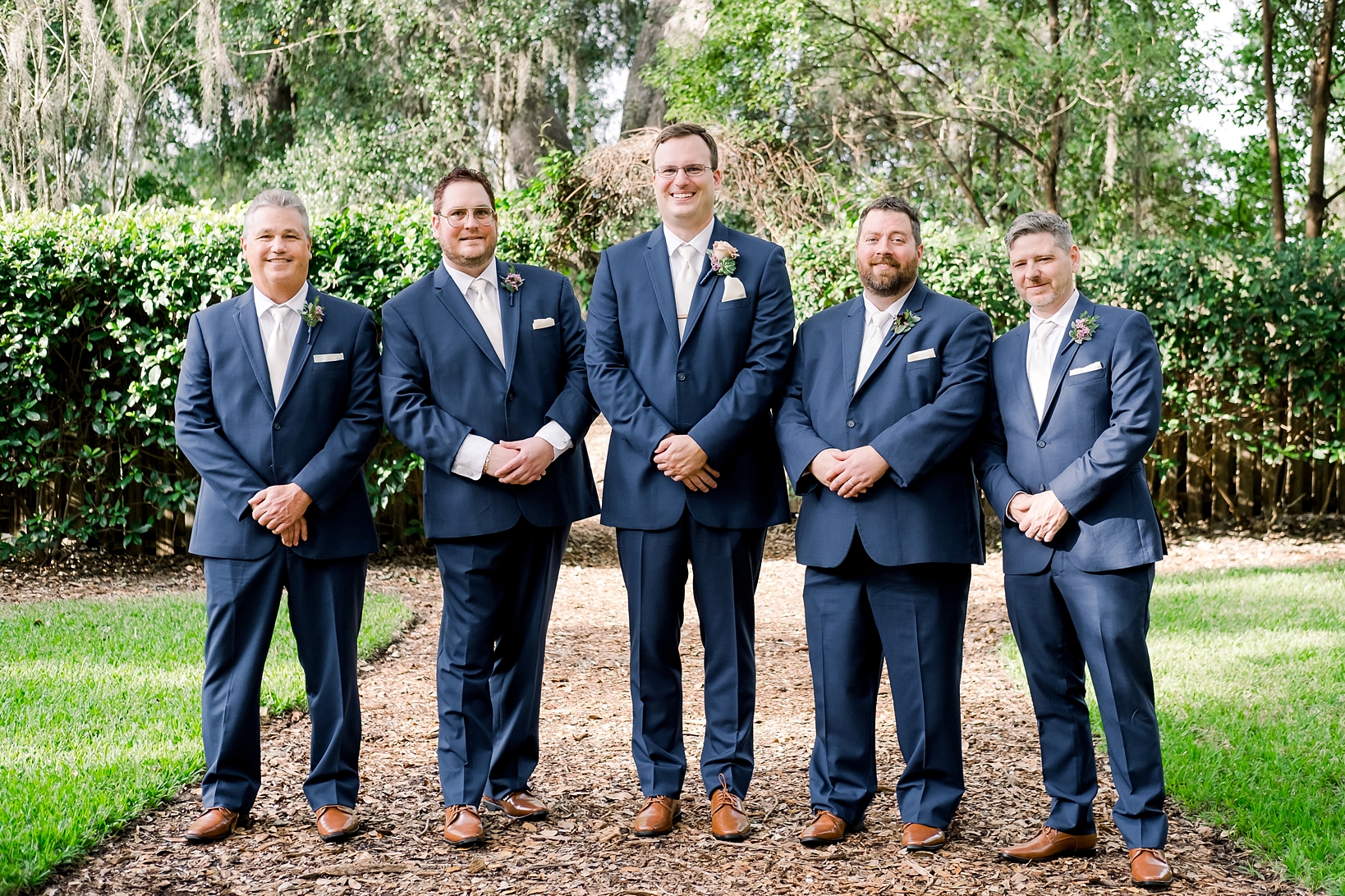 Groom and his Groomsmen pose for a formal photo on the mulch path