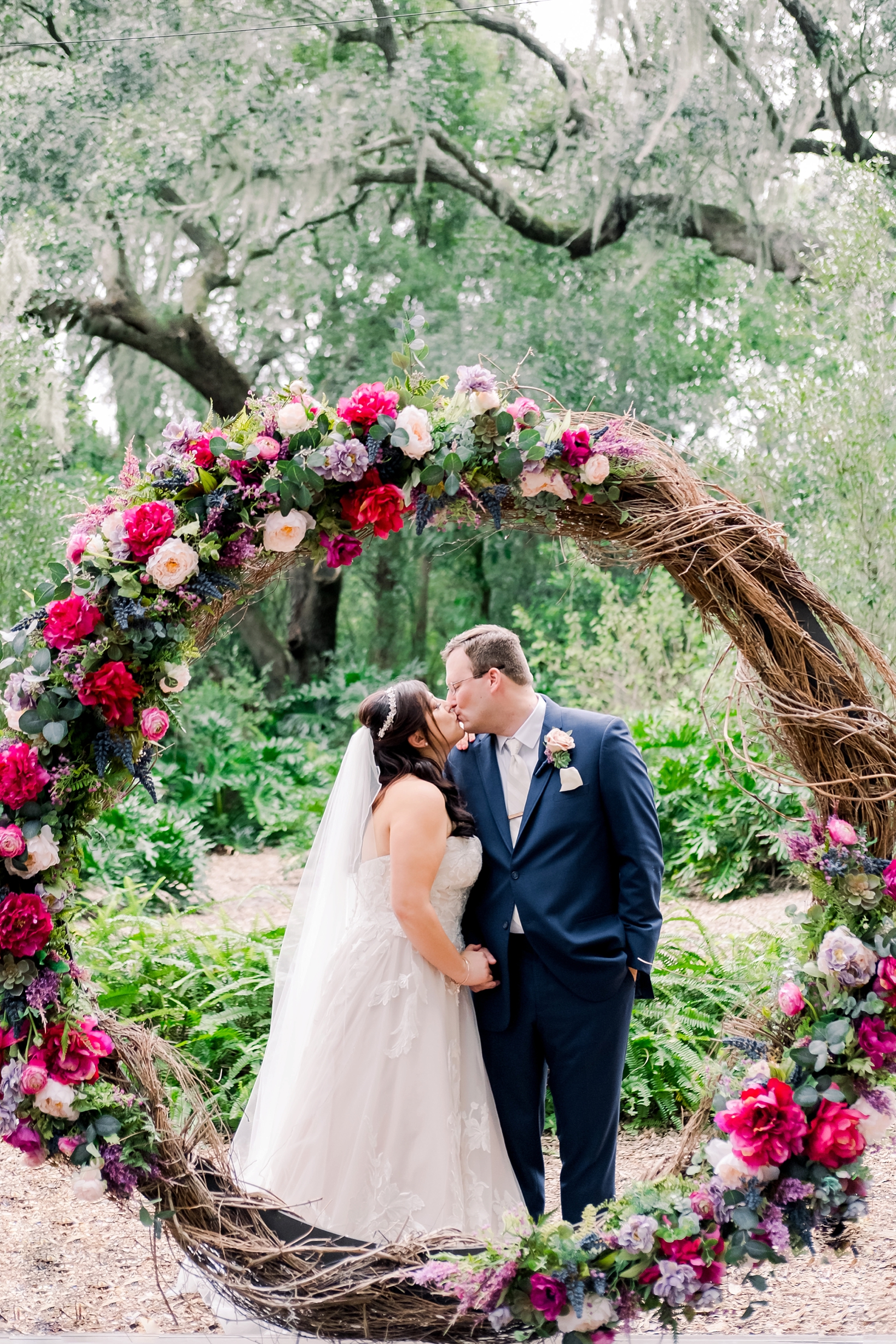 Bride and Groom kiss behind their large floral ring after their cross creek wedding
