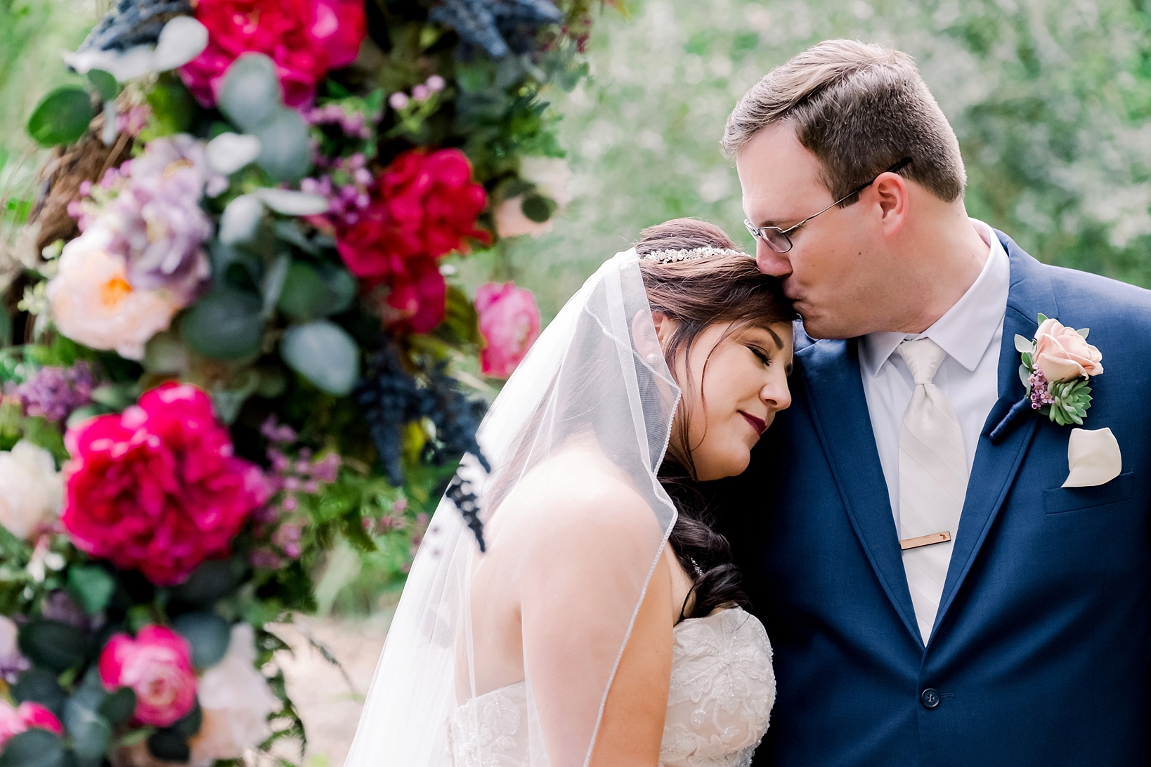 Bride nested into her grooms shoulder as he kisses her forehead in a quiet moment after the cross creek wedding
