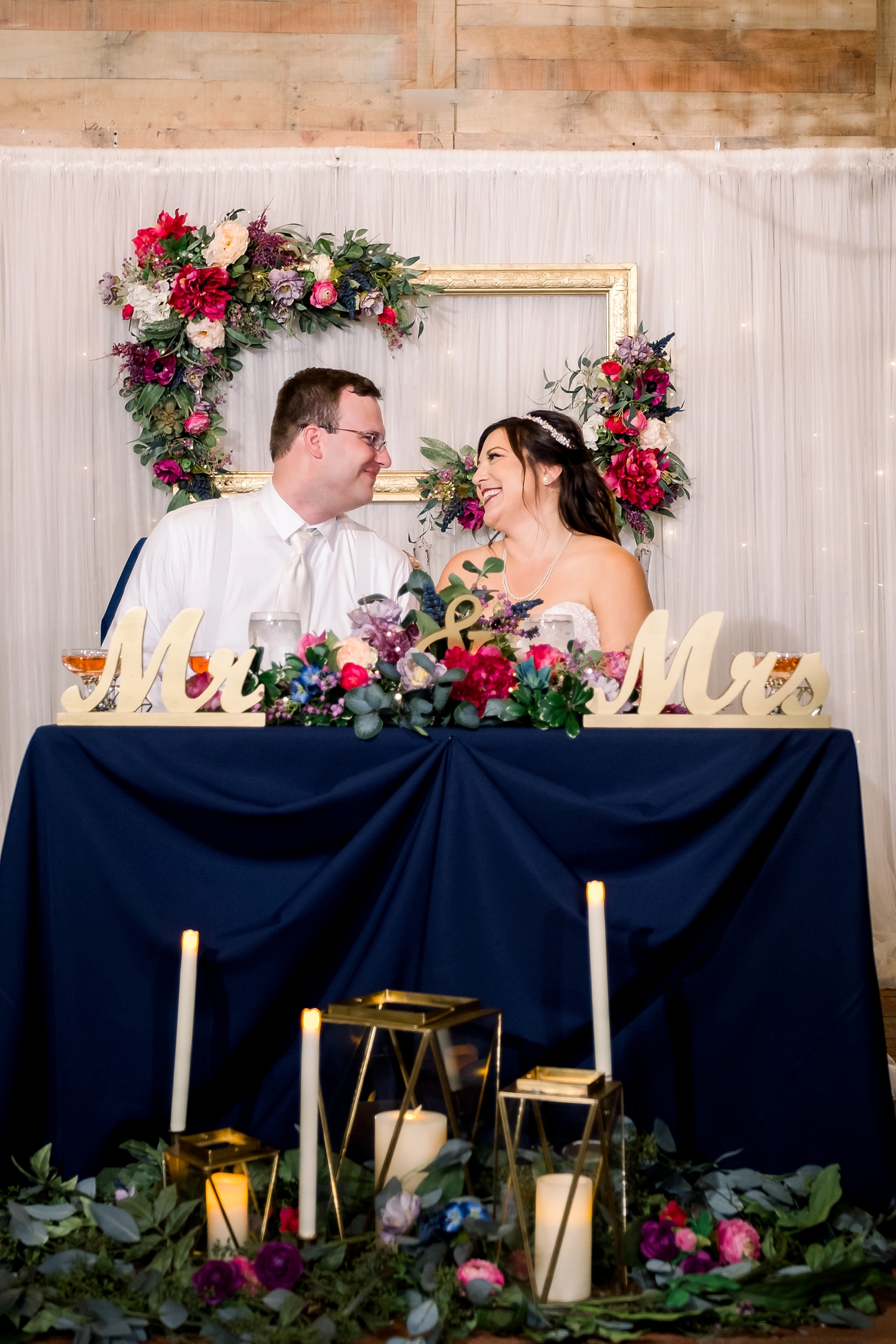 Newlyweds sit at their table exchanging a loving glance during their cross creek wedding reception