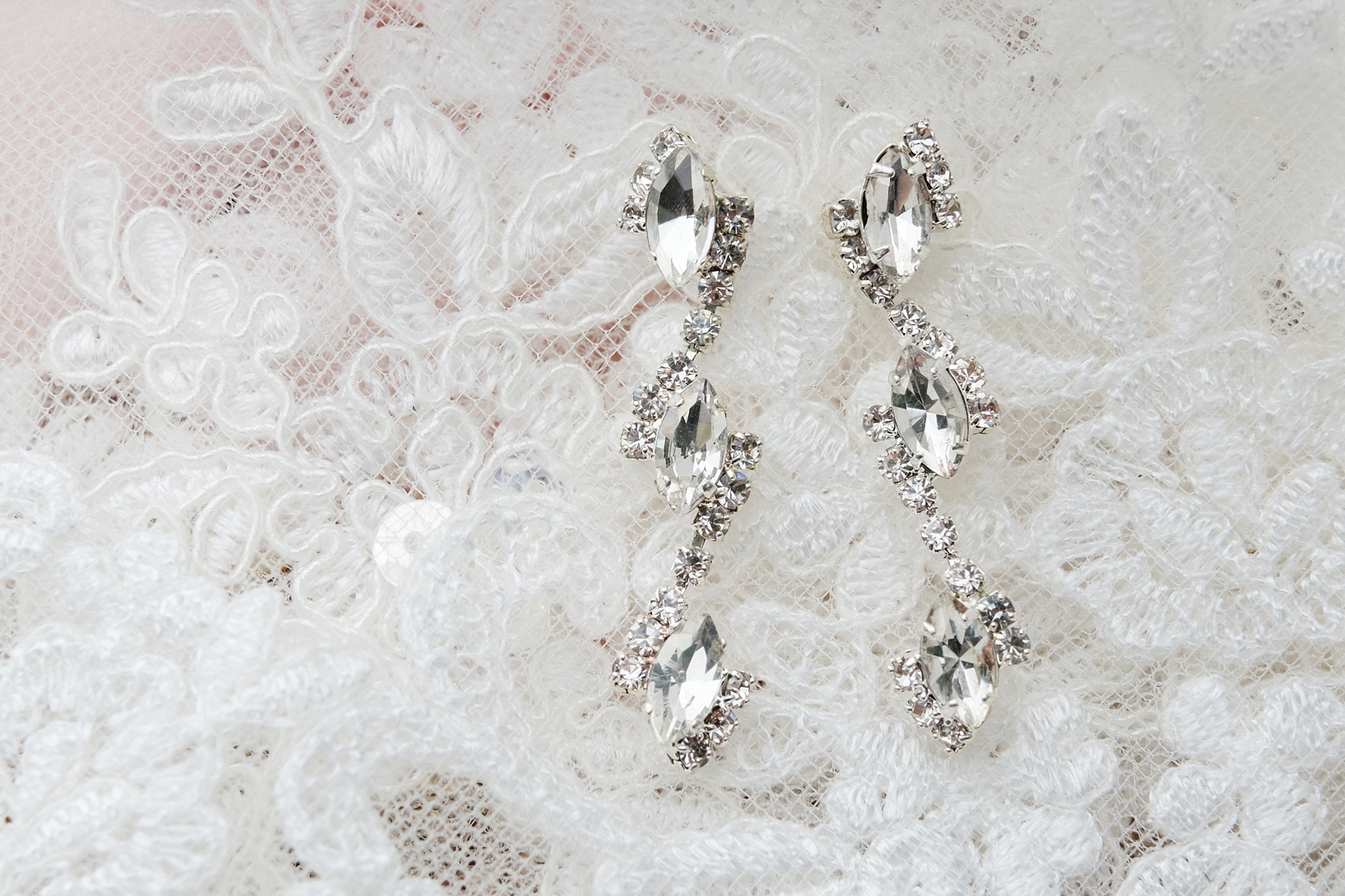 The Bride's diamond earrings against the background of the wedding veil by Sarah and Ben Photography