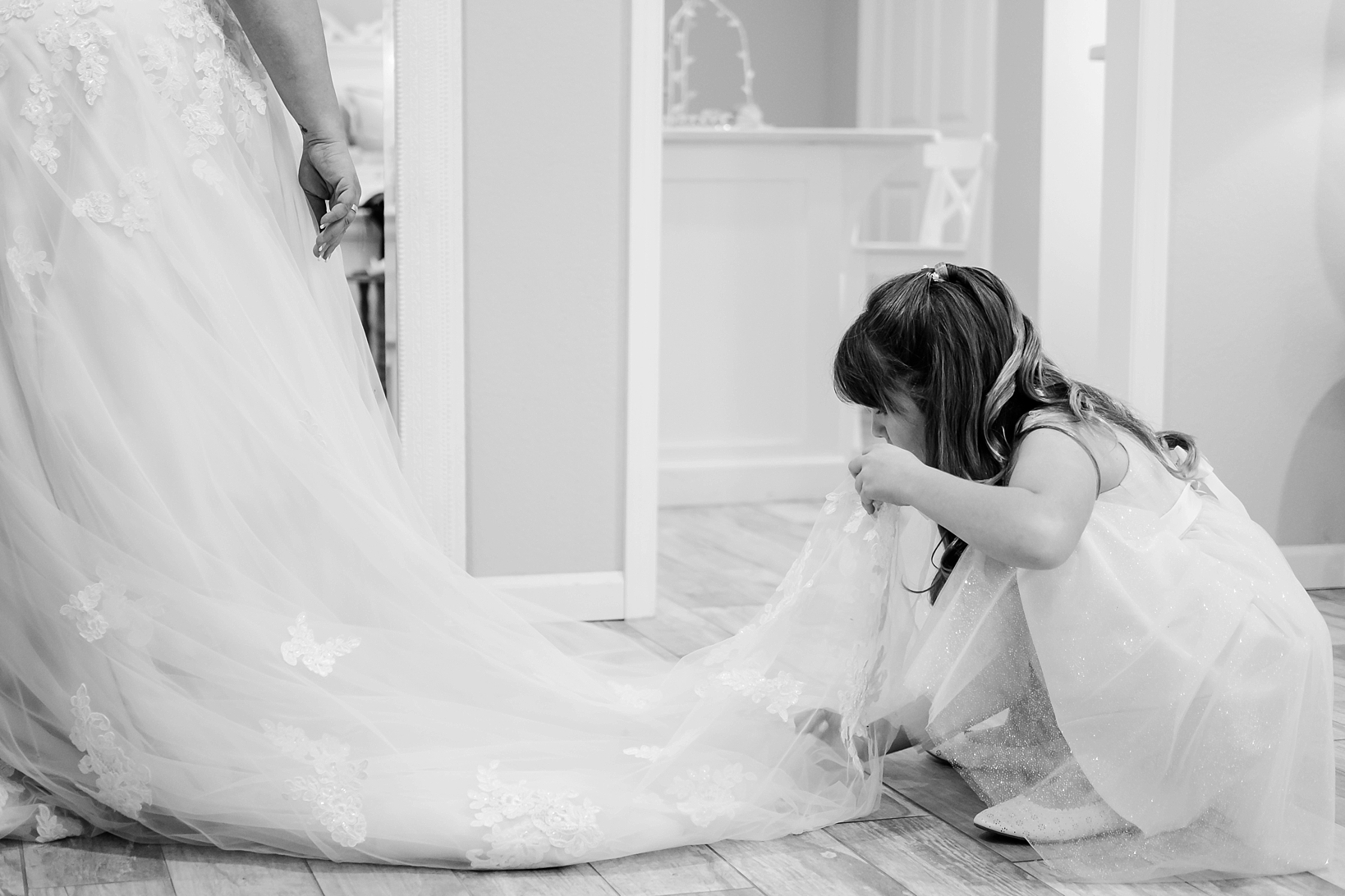 Flower girl helps adjust the cathedral veil of the Bride in classic black and white by Sarah and Ben Photography