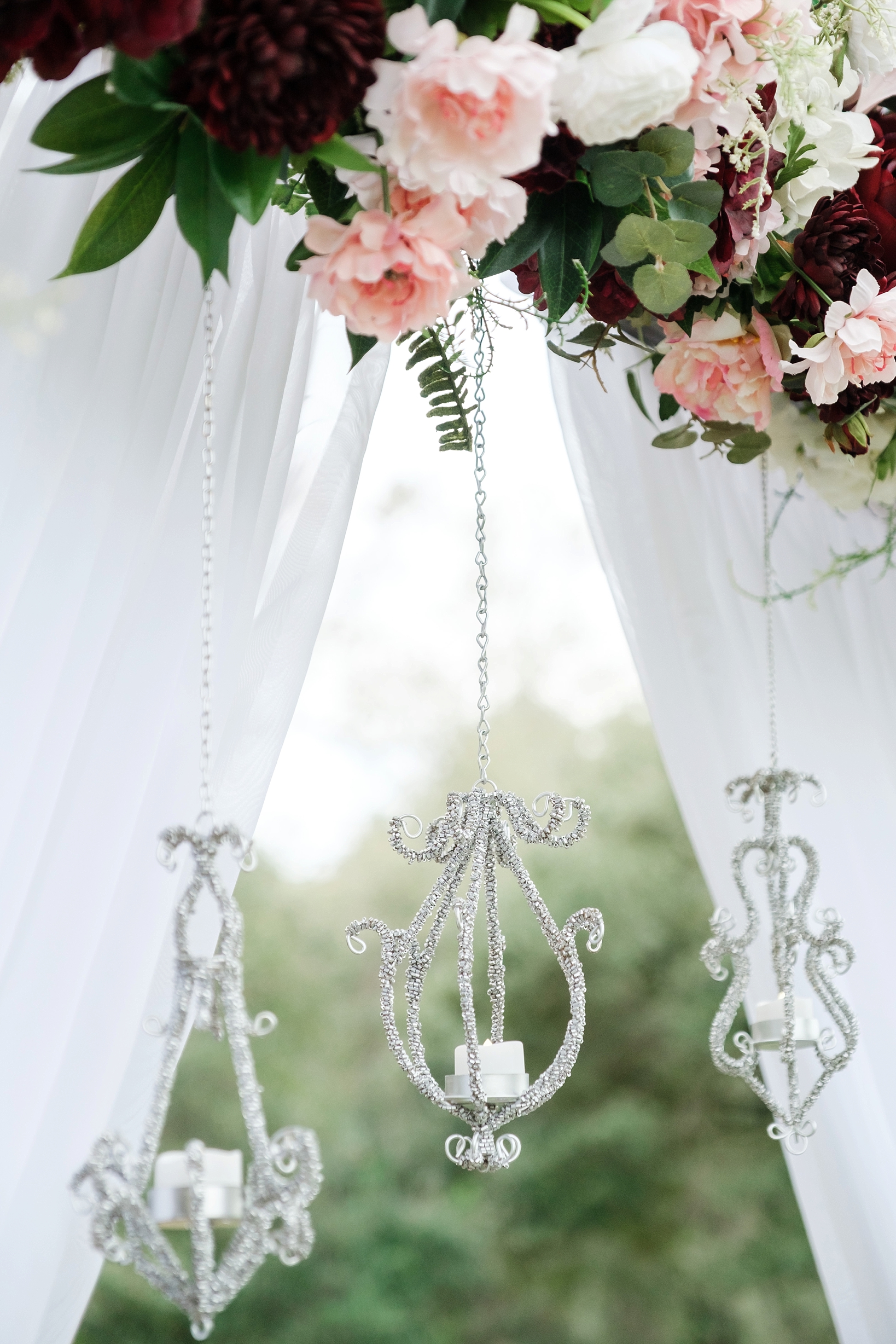 Small lanterns hand from the altar filled with florals and white tulle by Sarah and Ben Photography