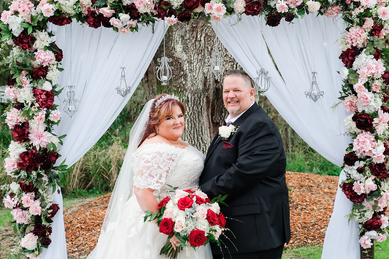 Bride and Groom pose for a formal photo under their floral arch at their cross creek wedding celebration