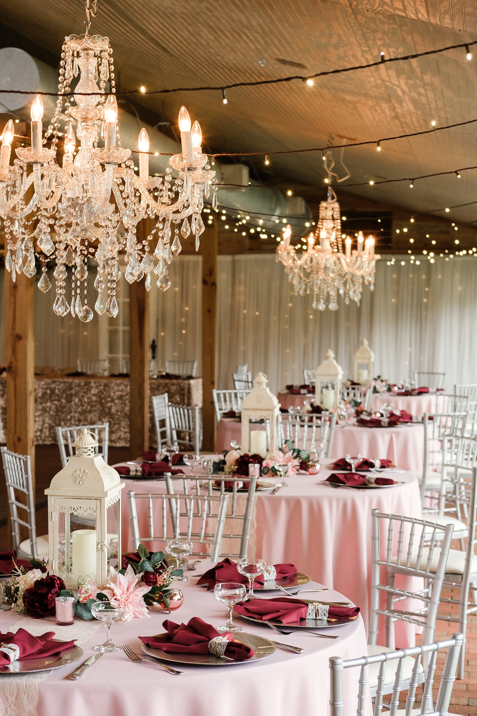 Tables and chandeliers fill the barn reception during this cross creek wedding celebration