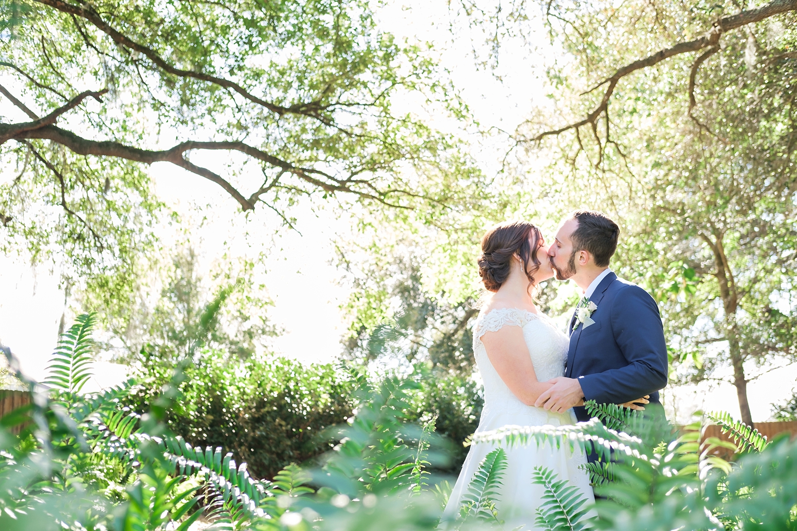 Bride and Groom kiss under the oak trees before their Cross Creek Ranch wedding