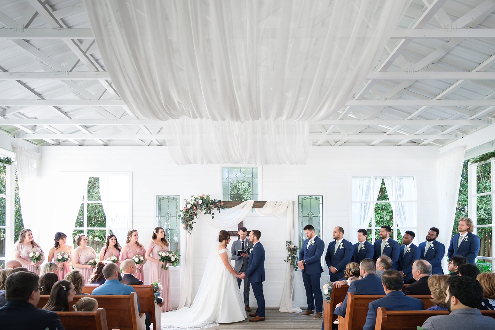 A wide shot of the entire wedding ceremony showing the entire wedding party standing at the altar