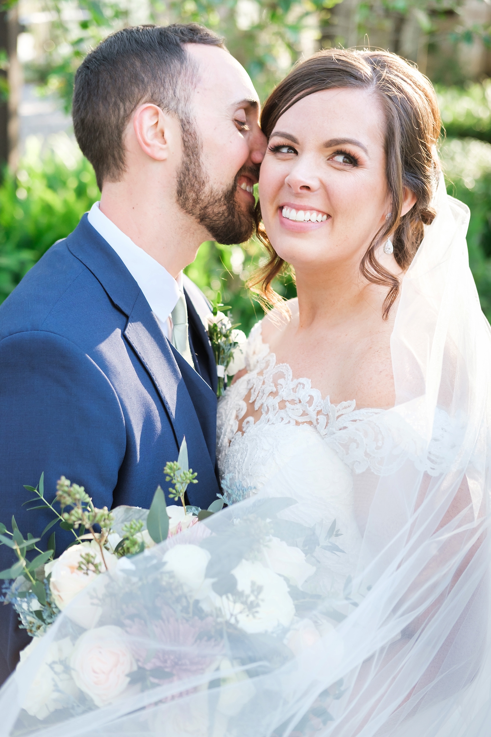 Groom whispers into his Bride's ear as she smiles
