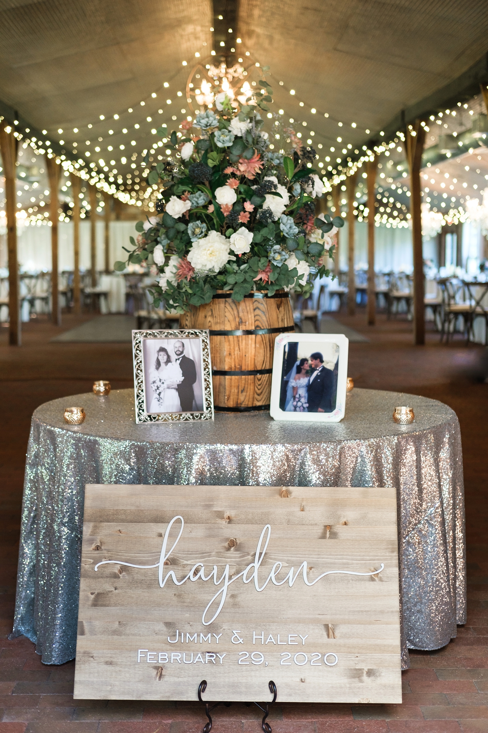 Welcome table greets guests with large florals, photos of the family and a large wooden sign