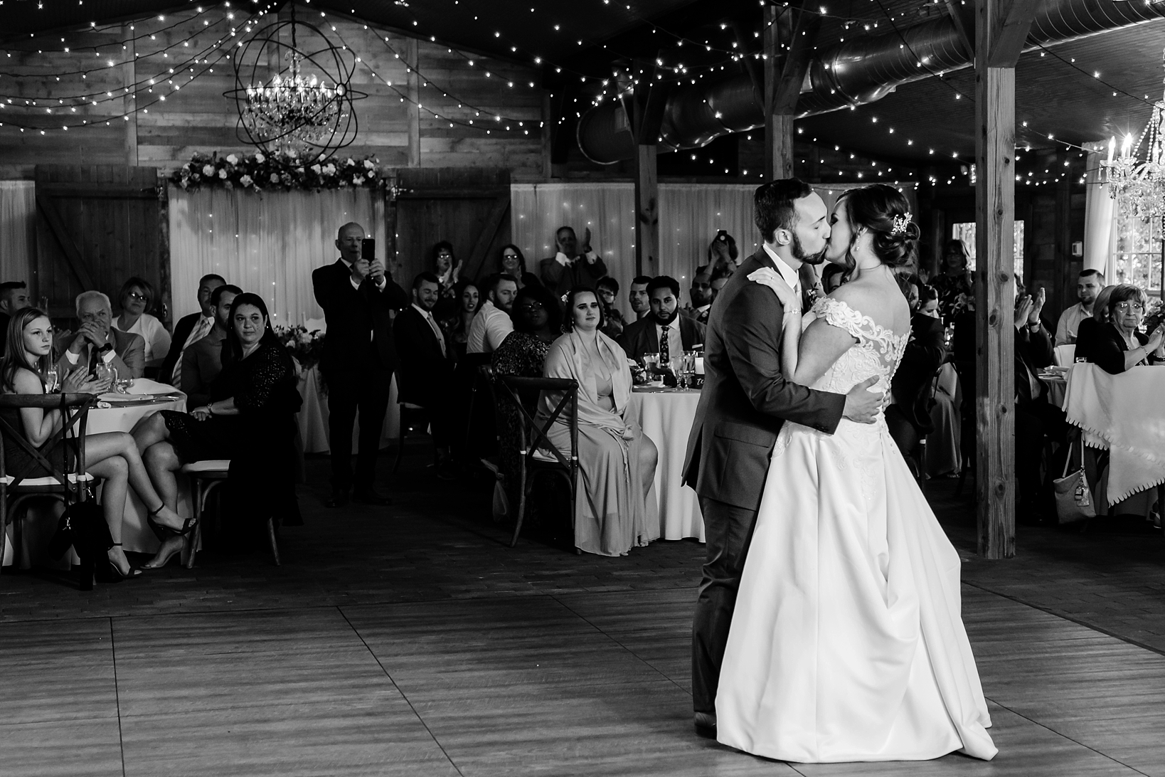 Bride and Groom kiss during their first dance as friends and family watch