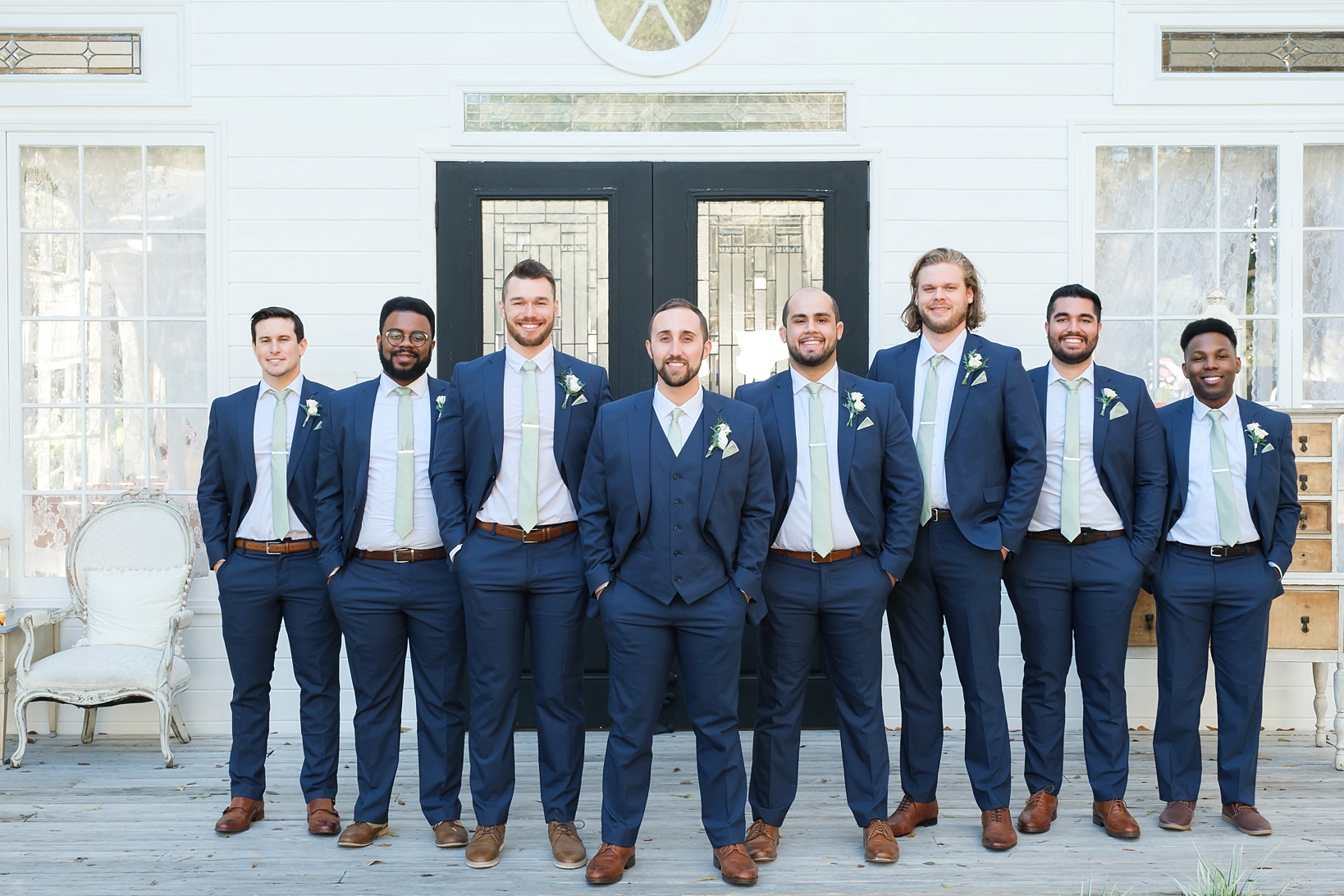 The Groom and his Groomsmen standing on the porch of the chapel at Cross Creek Ranch in navy blue suits