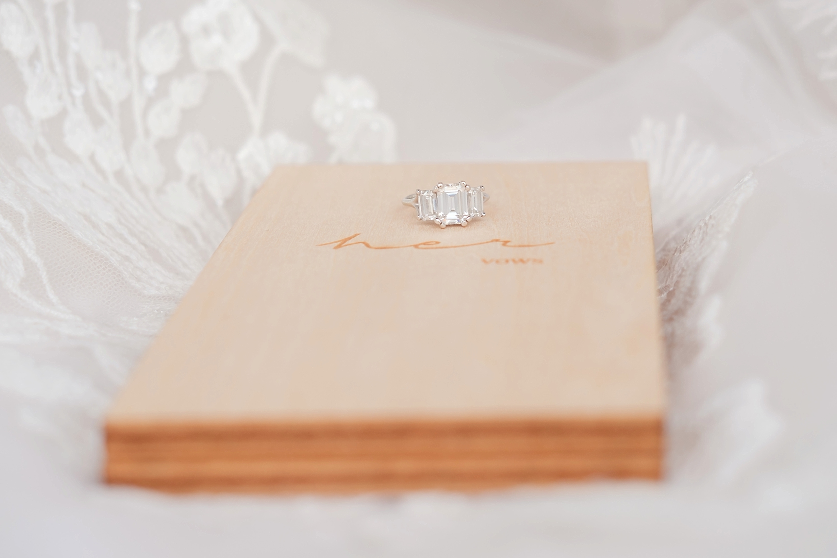 A brides vintage engagement ring sitting atop her vow book 