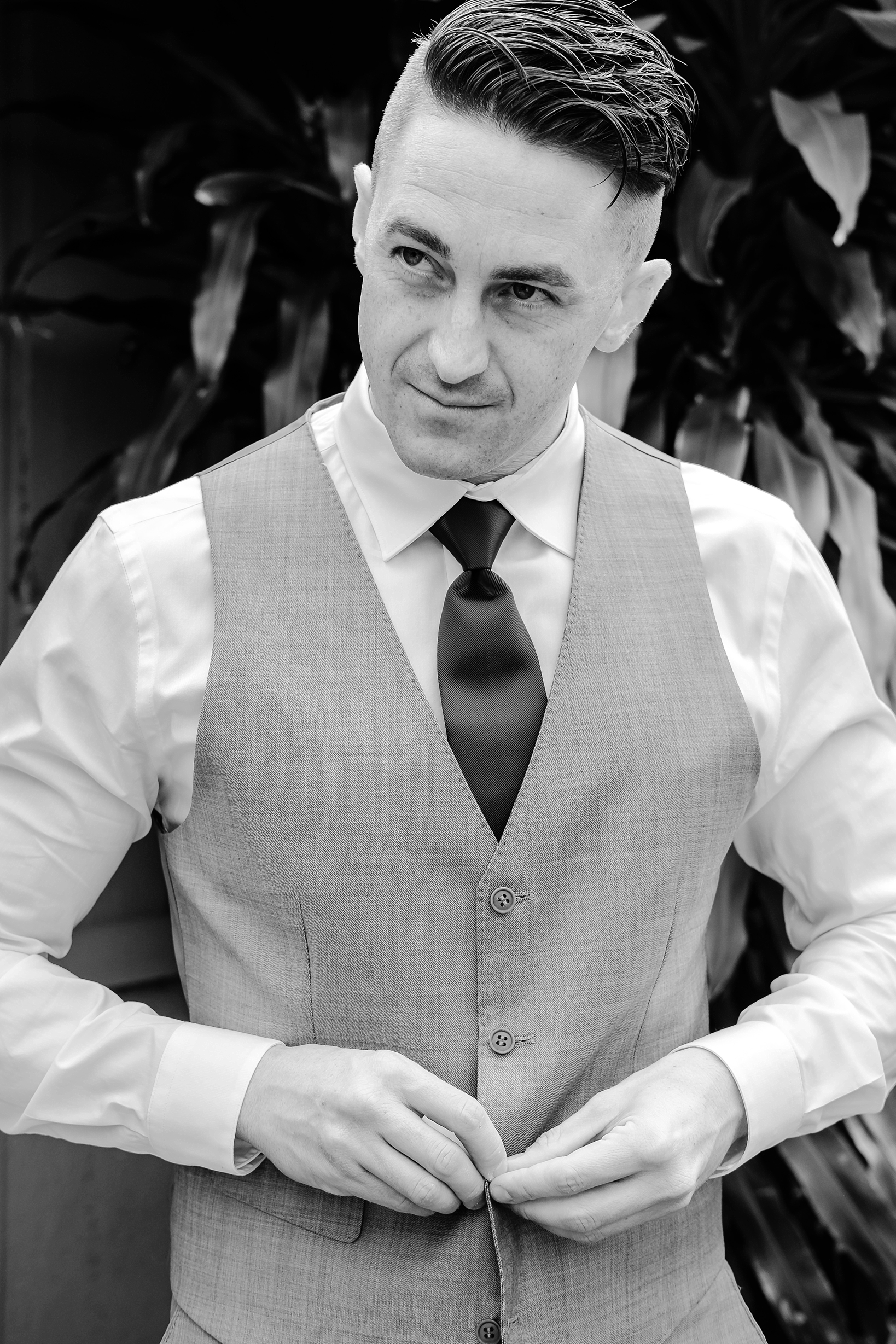 Groom putting his vest on in classic black and white