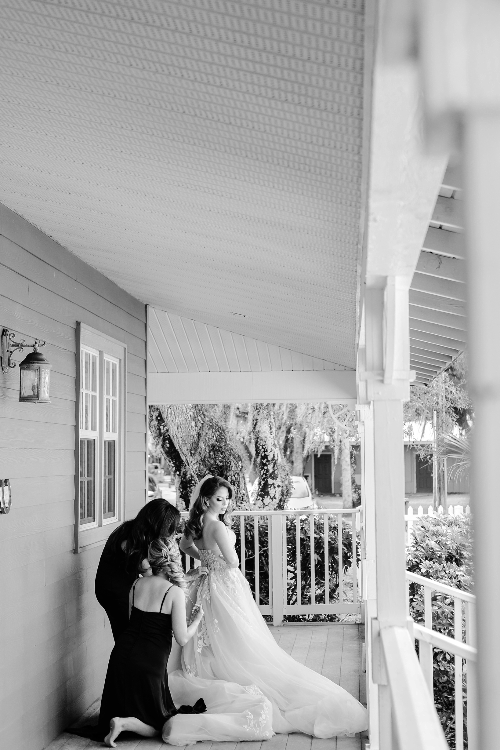 Bride photographed in black and white getting helped into her wedding dress