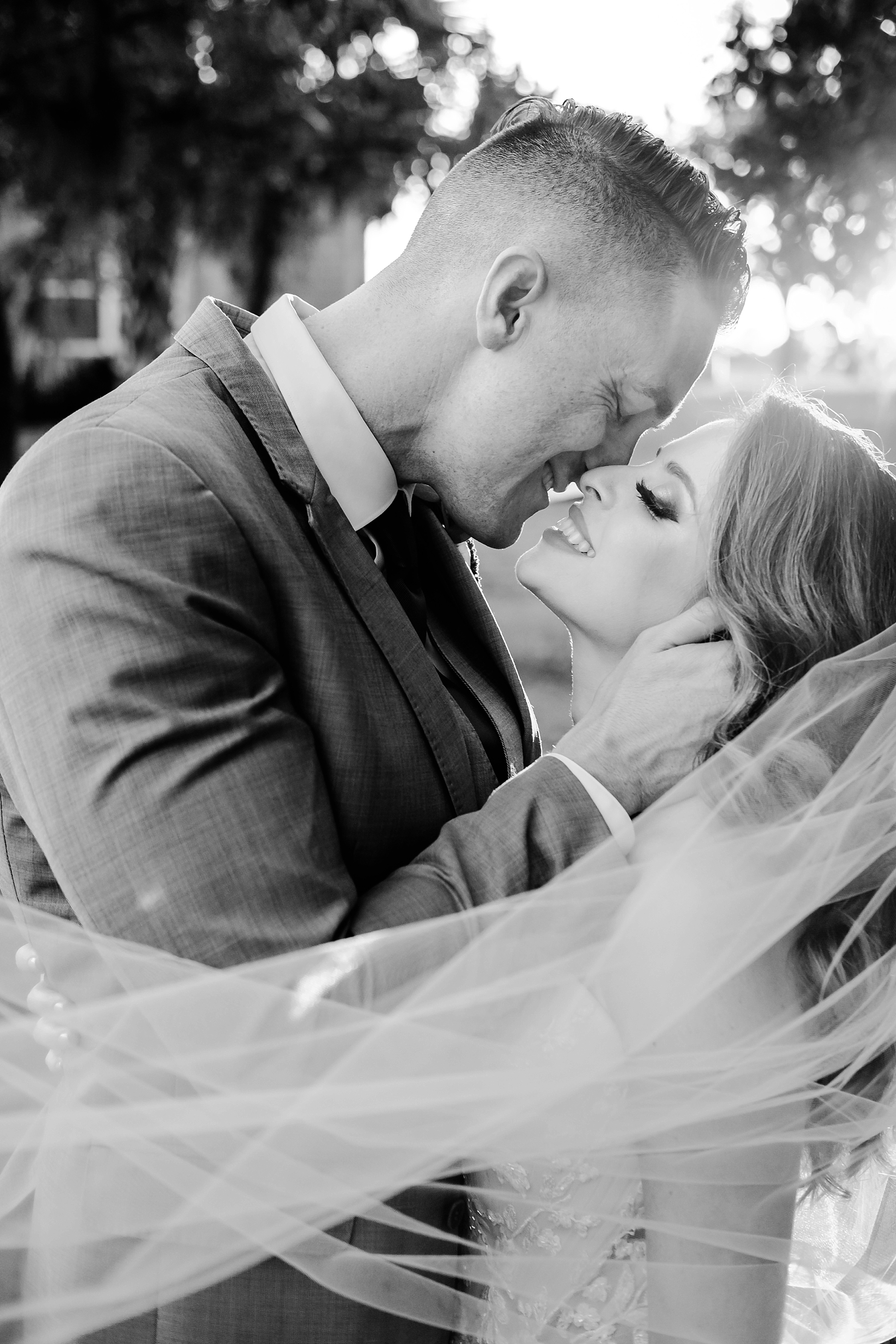 Stunning black and white photo of the bride and groom smiling right before they kiss