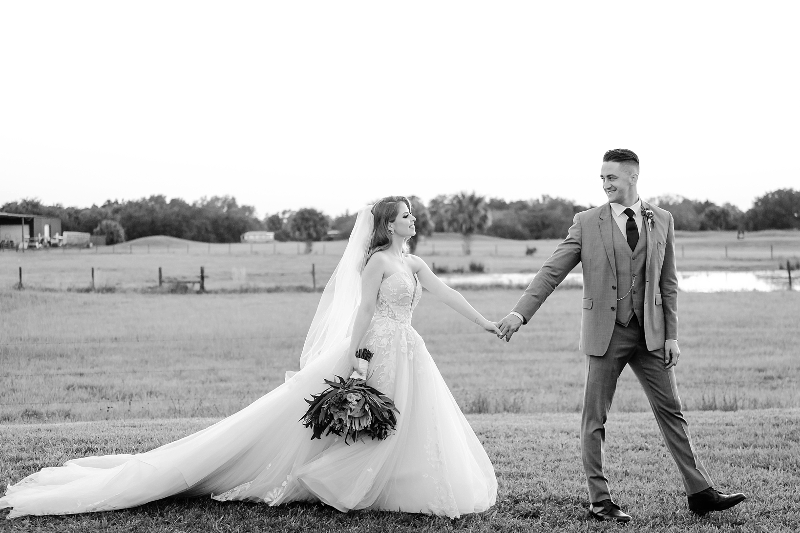 Groom guides Bride around the Ranch by her hand in Black and White