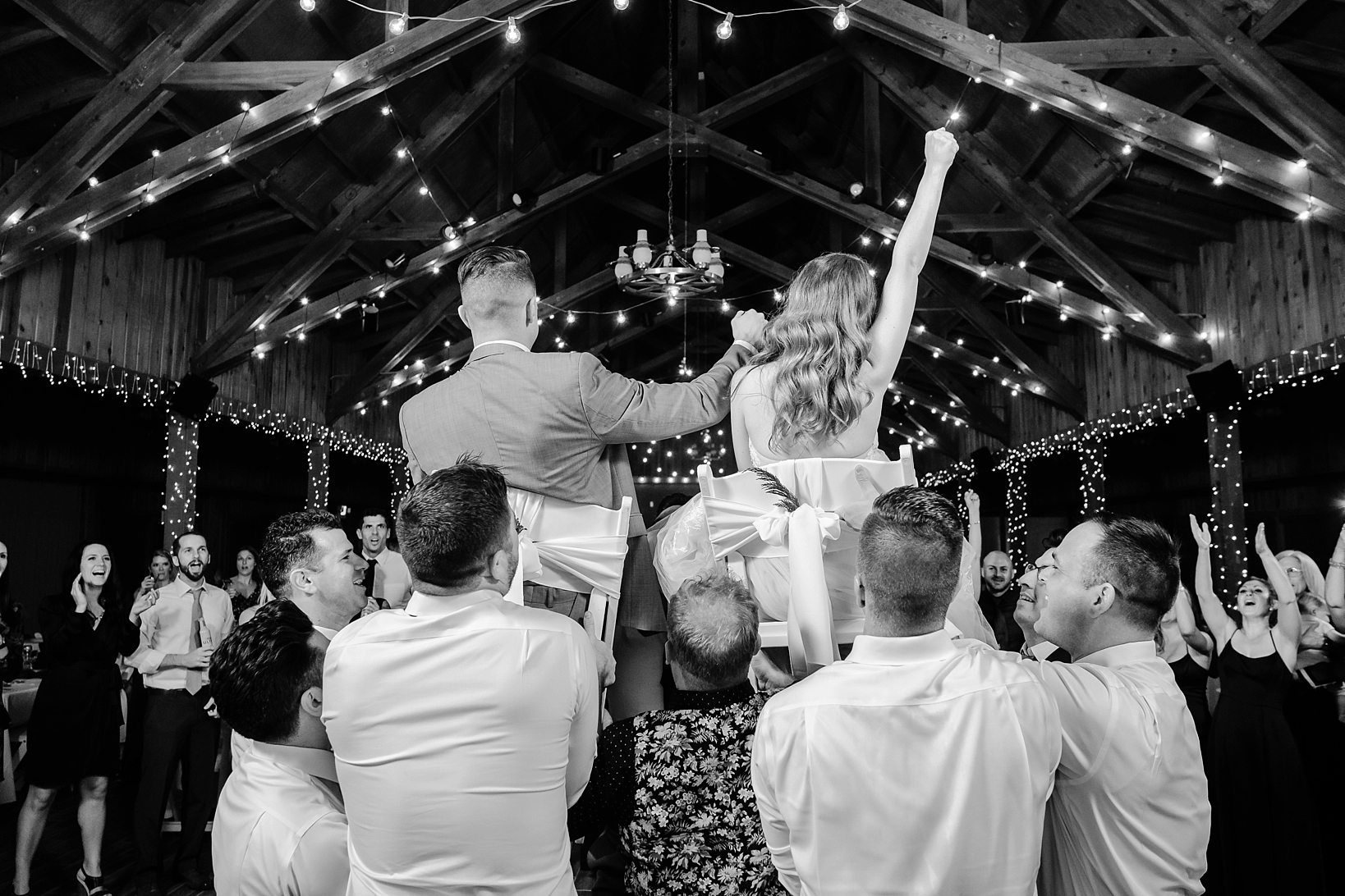 The Bride and Groom being lifted up during their wedding reception in chairs