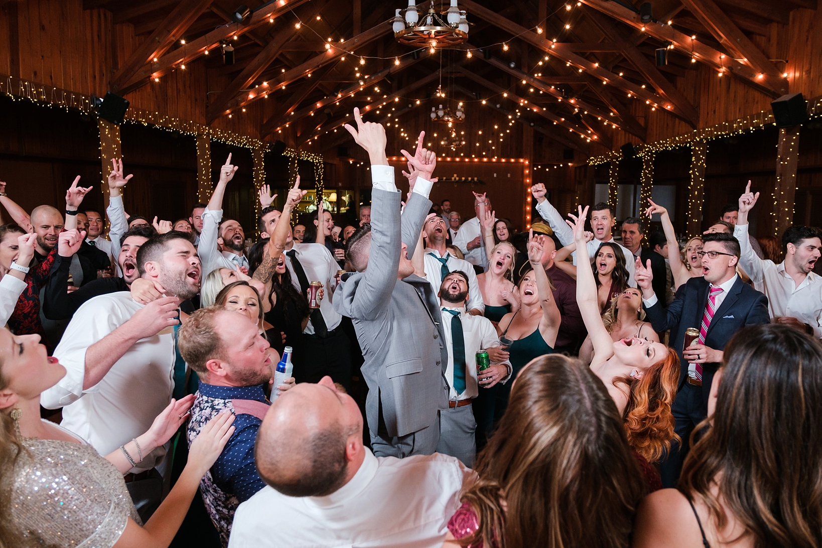 The dance party during the reception of the wedding as people throw their hands up in the air