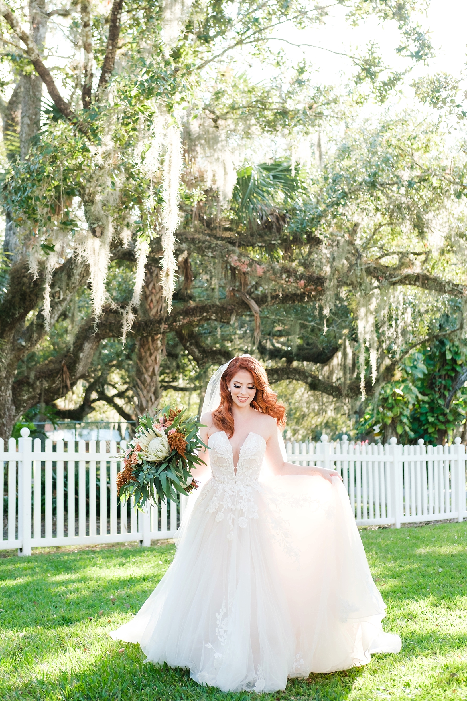 Bride walking in green grass while holding her dress