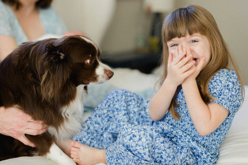 A girl laughs after being licked by her pet dog during her Family Photography Session